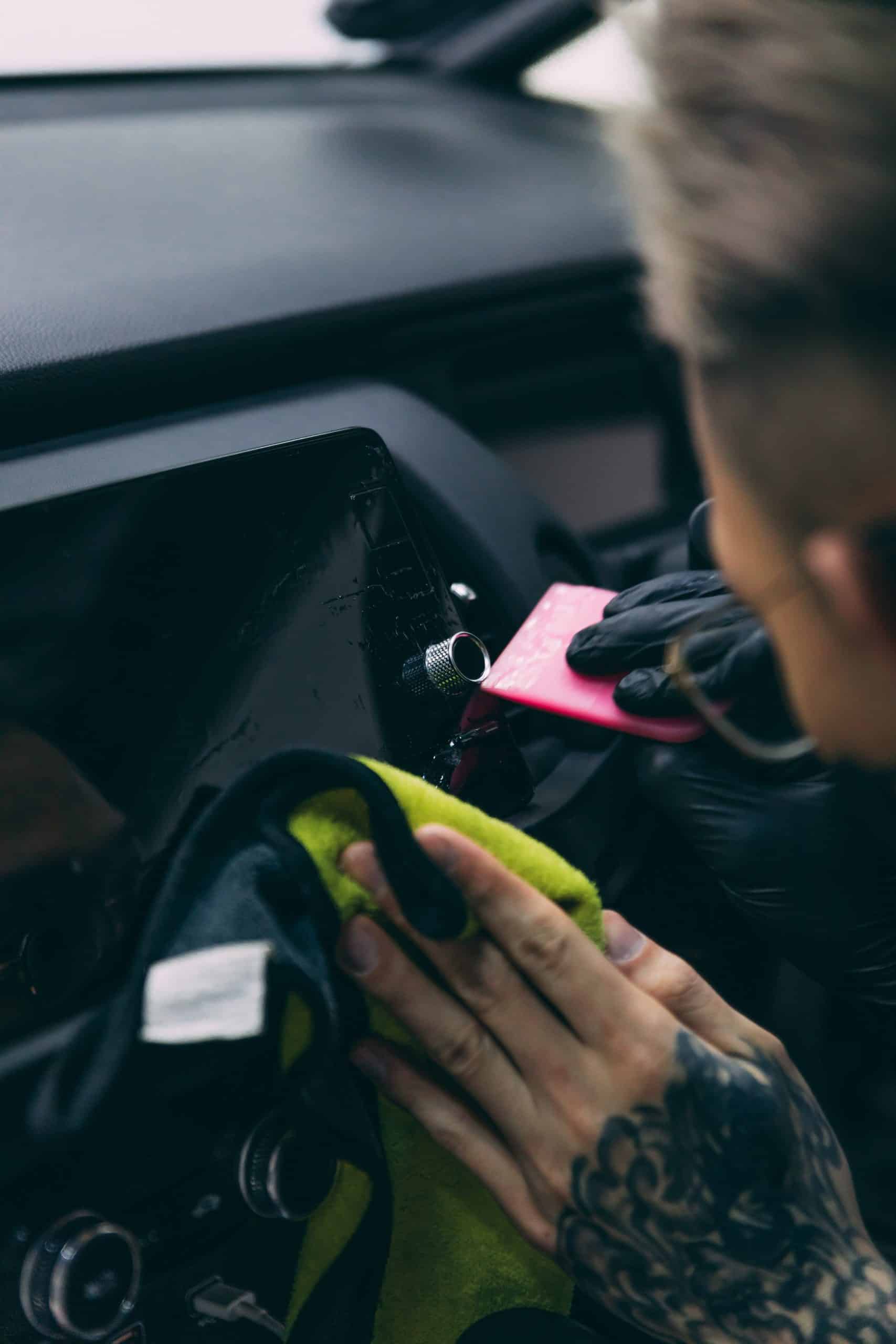 Technician applying clear protective film on BYD vehicle dashboard.